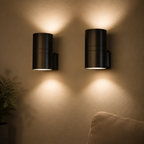 Two black plug in night lights cast warm beams across a softly textured wall.