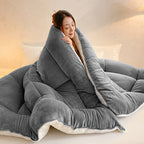 Gray comforter wrapped around a seated woman showing the ivory reverse