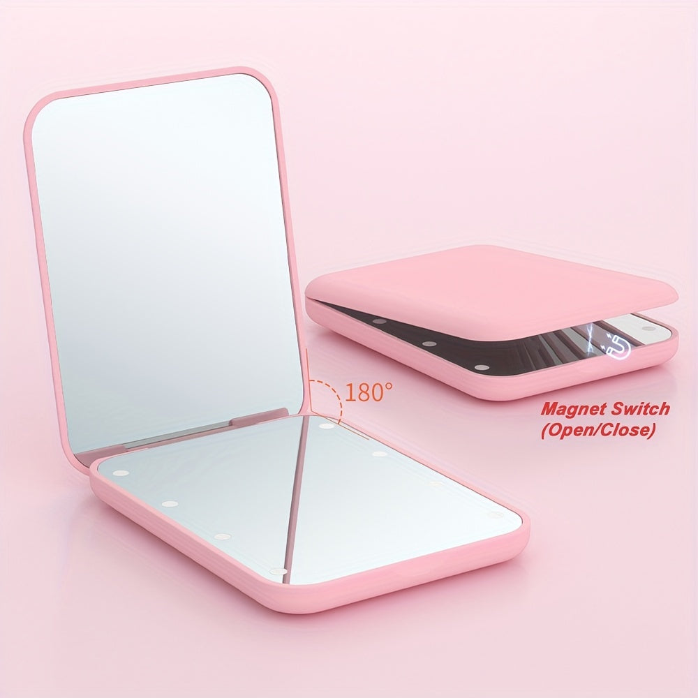 Pink pocket makeup mirror open at a tabletop angle with both mirror surfaces visible.