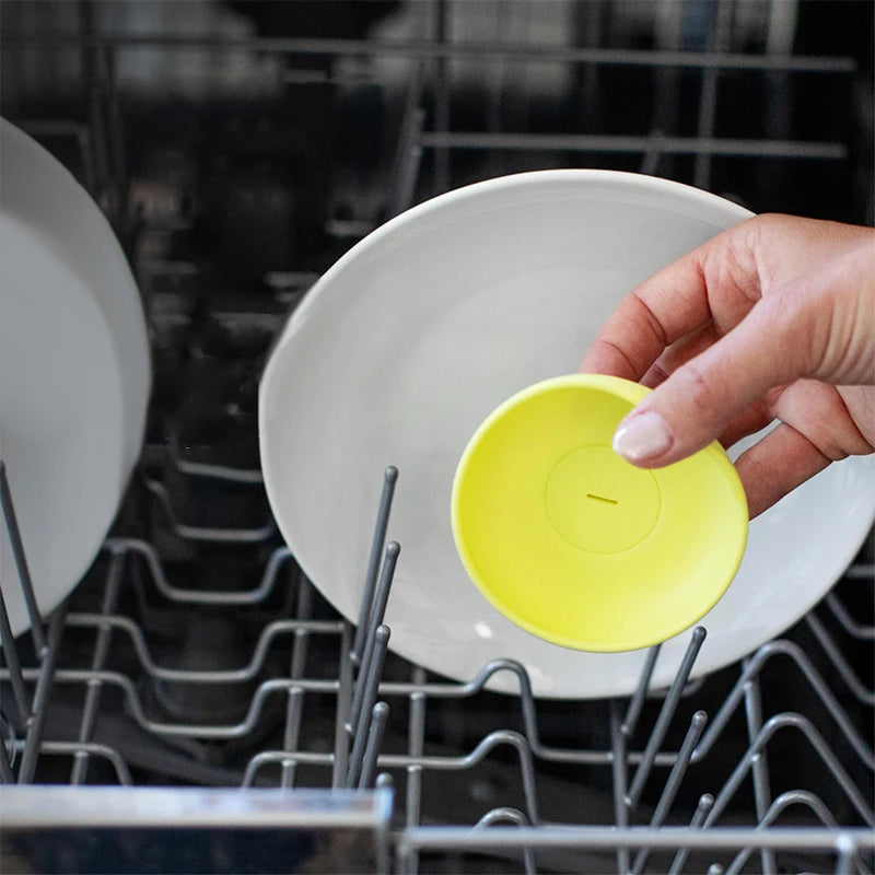 Yellow popsicle holder placed beside dishes in a dishwasher