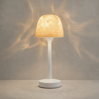 White portable ambient lamp projecting warm ripples against a cool gray studio wall