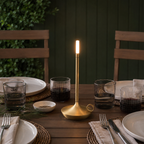 Gold portable table lamp glowing on a set dining table.