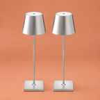 Two silver portable table lamps on a terracotta studio background