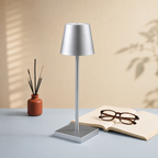 Silver portable table lamp beside a reed diffuser and reading glasses