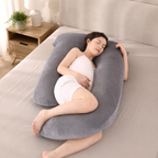 Gray U shaped pregnancy pillow shown around a fully clothed adult in bed.