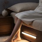 White motion sensor light illuminating an oak bed-frame drawer at night