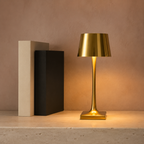 Gold rechargeable table lamp beside plain books on a limestone console