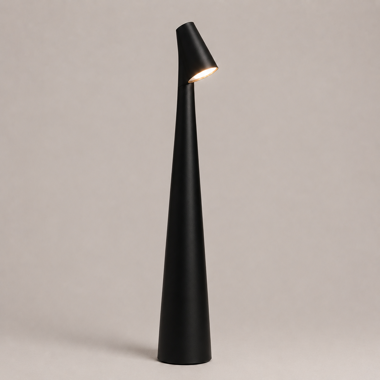 Black table lamp with a tapered cone body and angled light head on a neutral studio background.