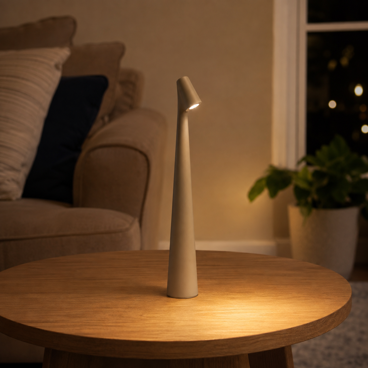 Golden brown table lamp illuminating a round wooden table beside a lounge chair and plant.