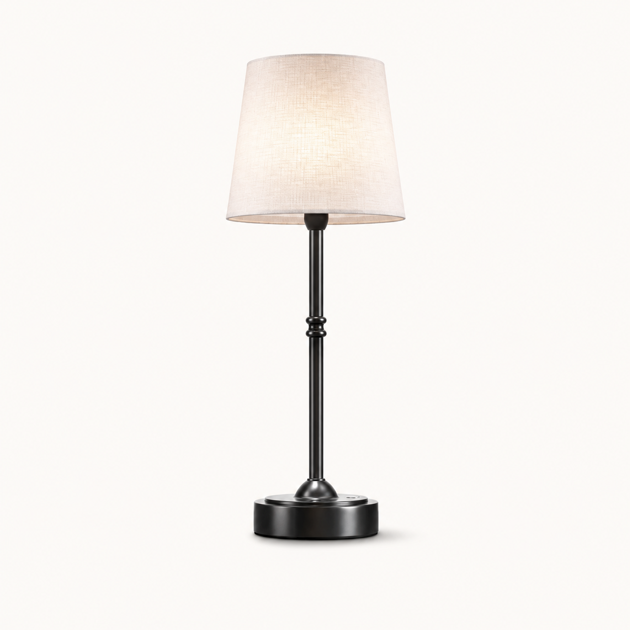 A modern table lamp with a tapered off-white fabric shade, a slim black metal stem with decorative bead details, and a round black base, shown against a plain off-white background.