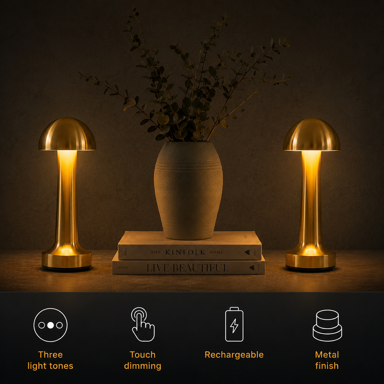 Two gold dome table lamp units glowing beside a vase and stacked books.