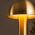 Close-up of a glowing gold dome table lamp shade and tapered stem.