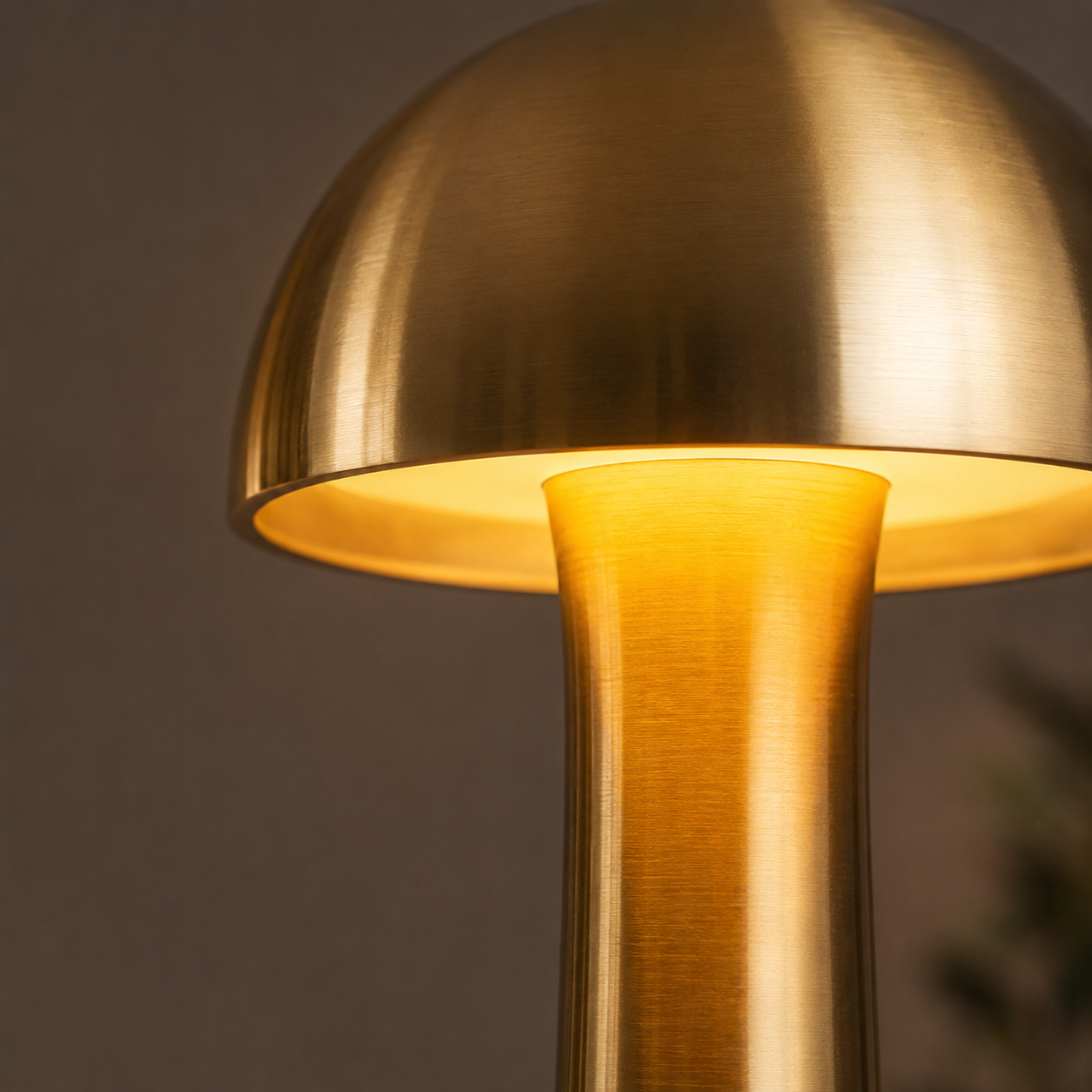 Close-up of a glowing gold dome table lamp shade and tapered stem.