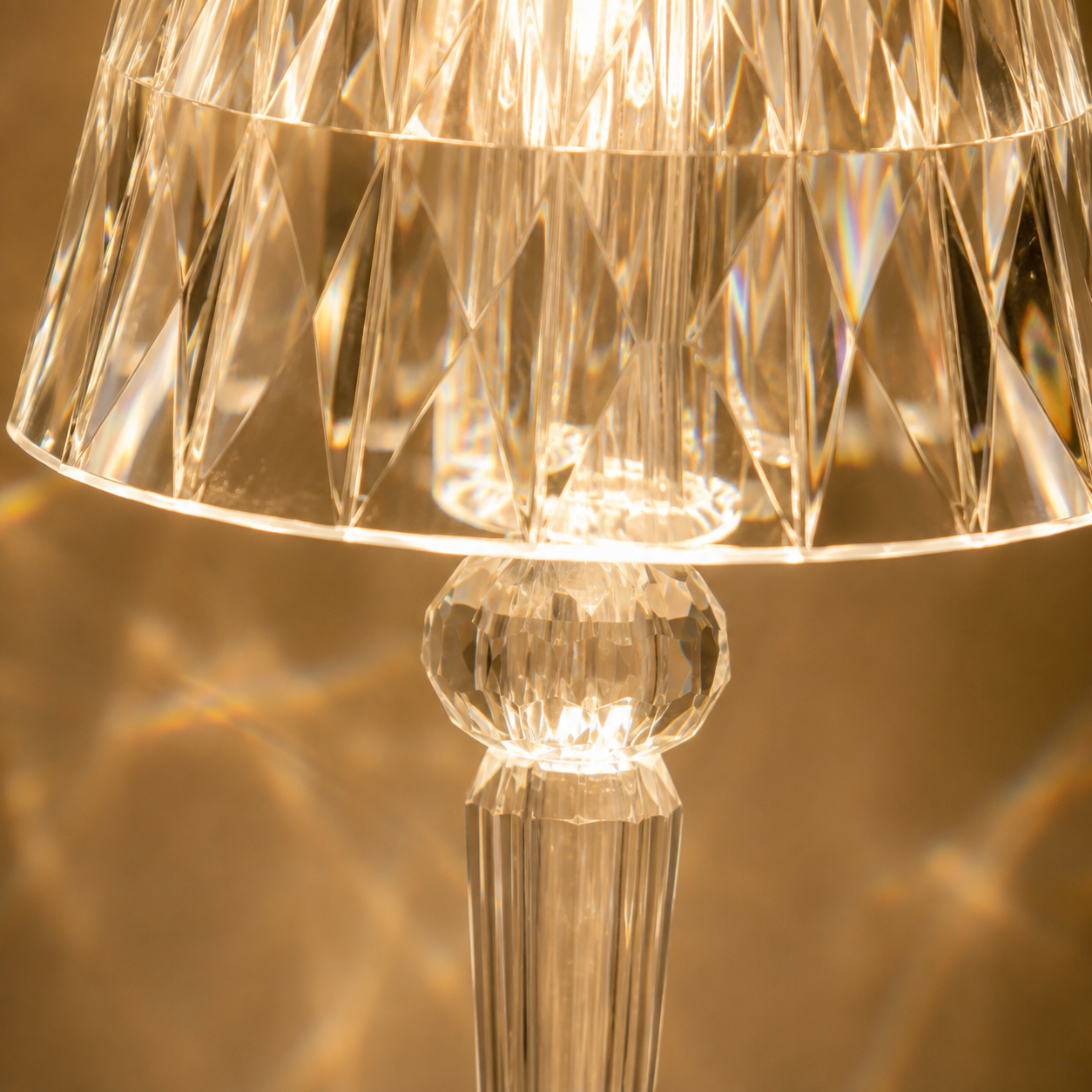 Close-up of the table lamp shade and round neck detail, highlighting the faceted transparent surface and warm glow.
