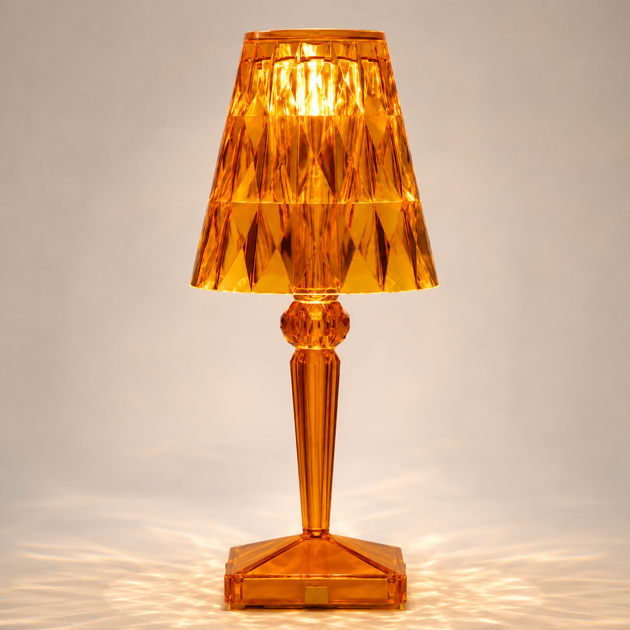Amber transparent table lamp with a faceted shade and square base on a light background.