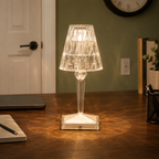 Table lamp glowing on a wooden console near a doorway, with a clock and small decor visible in the room.