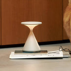 White rechargeable table lamp standing on books beside glasses.