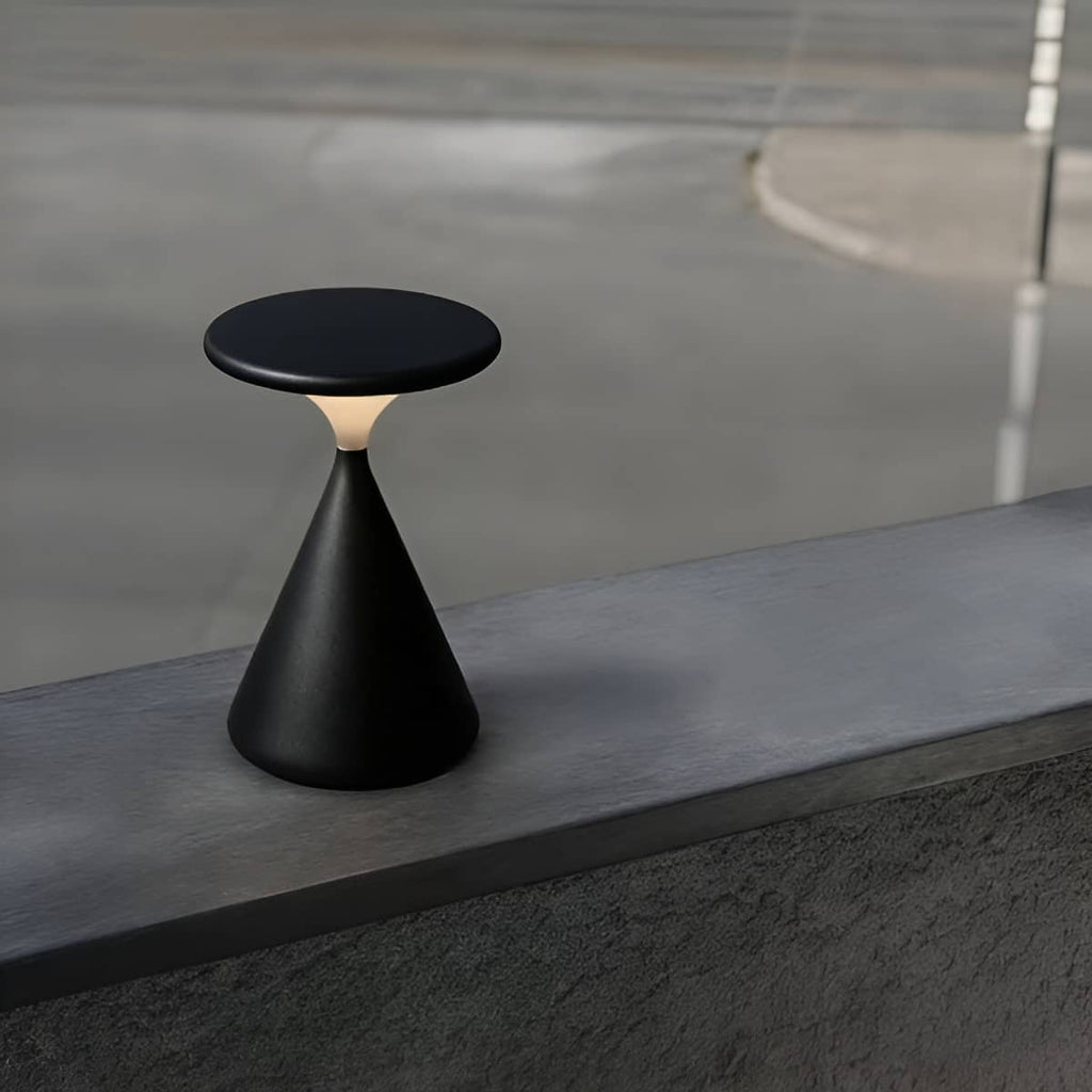Black rechargeable table lamp on a concrete ledge.
