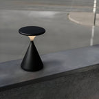Black rechargeable table lamp on a concrete ledge.