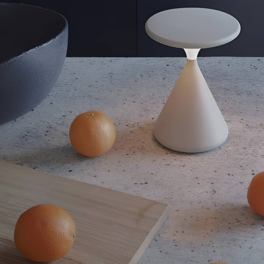 White rechargeable table lamp on a speckled counter beside oranges.