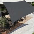 Dark gray rectangular shade sail stretched above a patio table.
