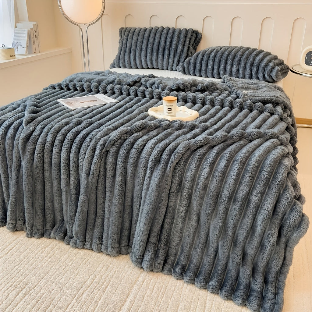 Dark Gray plush throw with a folded edge on a bed