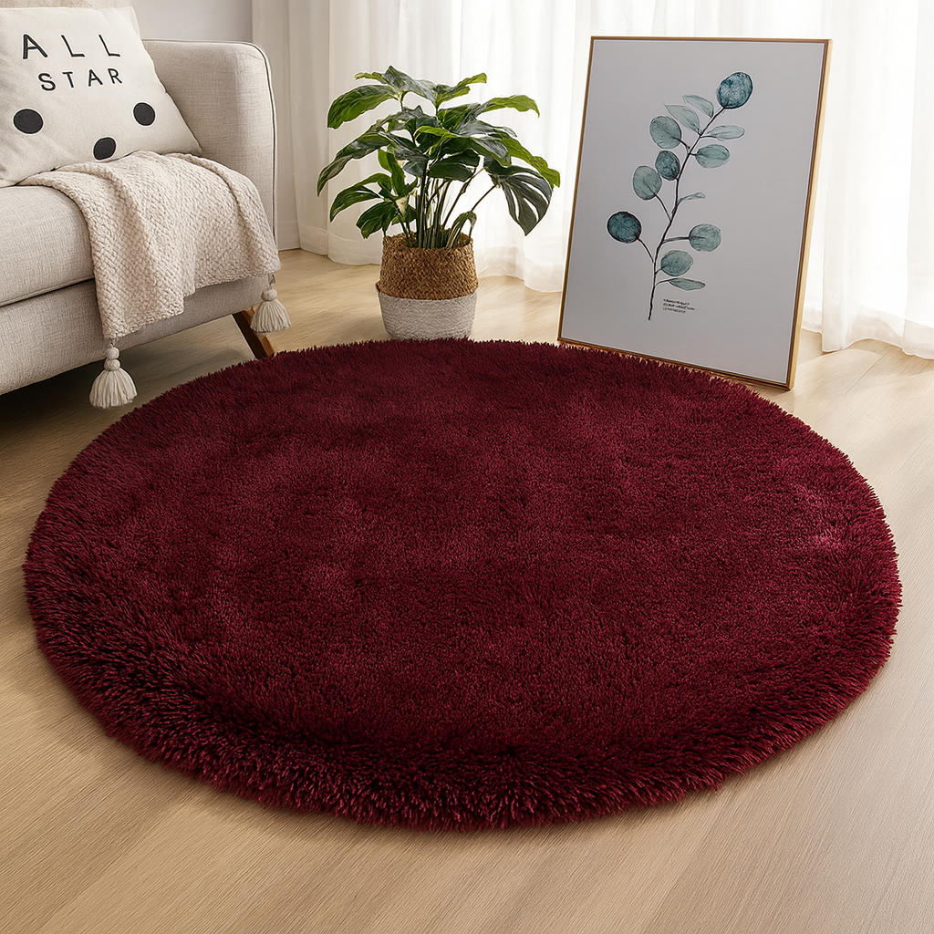 Wine red round area rug styled beside a chair and botanical print.