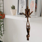 Bronze resin figures displayed on a white shelf with framed artwork