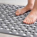 Non slip shower mat in gray beneath wet feet with water across the surface