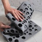 Non slip shower mat folded by two hands to show its flexible rubber construction