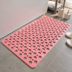 Non slip shower mat in pink laid flat beside a white bathtub