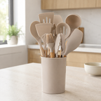 Beige silicone cooking utensil set stands in a matching holder on a bright kitchen island.