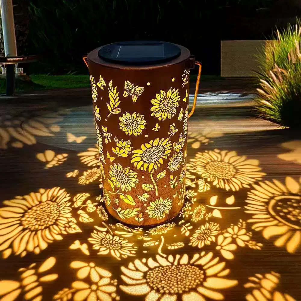 Black solar garden lantern projecting warm white floral shadows.