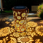 Black solar garden lantern projecting warm white floral shadows.