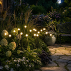Warm white solar garden lights glowing beside flowers and a garden bench.