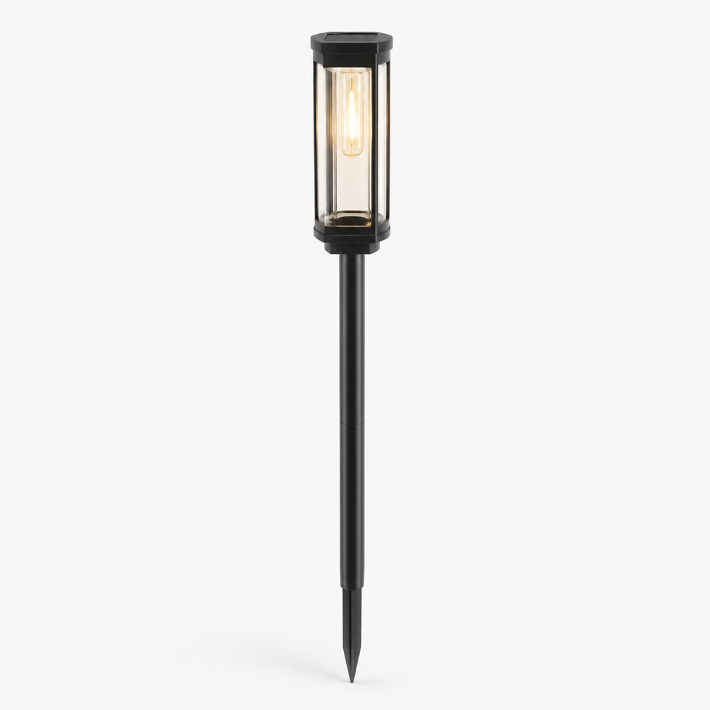 A modern black metal solar landscape light with a glass cylinder shade and a long stake, shown lit against a plain white background.