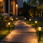 Outdoor solar pathway lights illuminating a stone walkway leading to a house at night, with grass, plants, and landscaping visible.