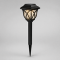A black solar-powered outdoor landscape light with a pointed stake base and a textured glass shade, shown illuminated against a neutral gray background.