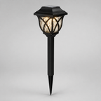 A black solar-powered outdoor landscape light with a pointed stake base and a textured glass shade, shown illuminated against a neutral gray background.