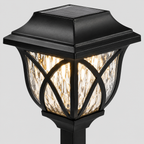 A black solar-powered outdoor post cap light with a warm glowing seeded glass shade, shown against a solid gray background.