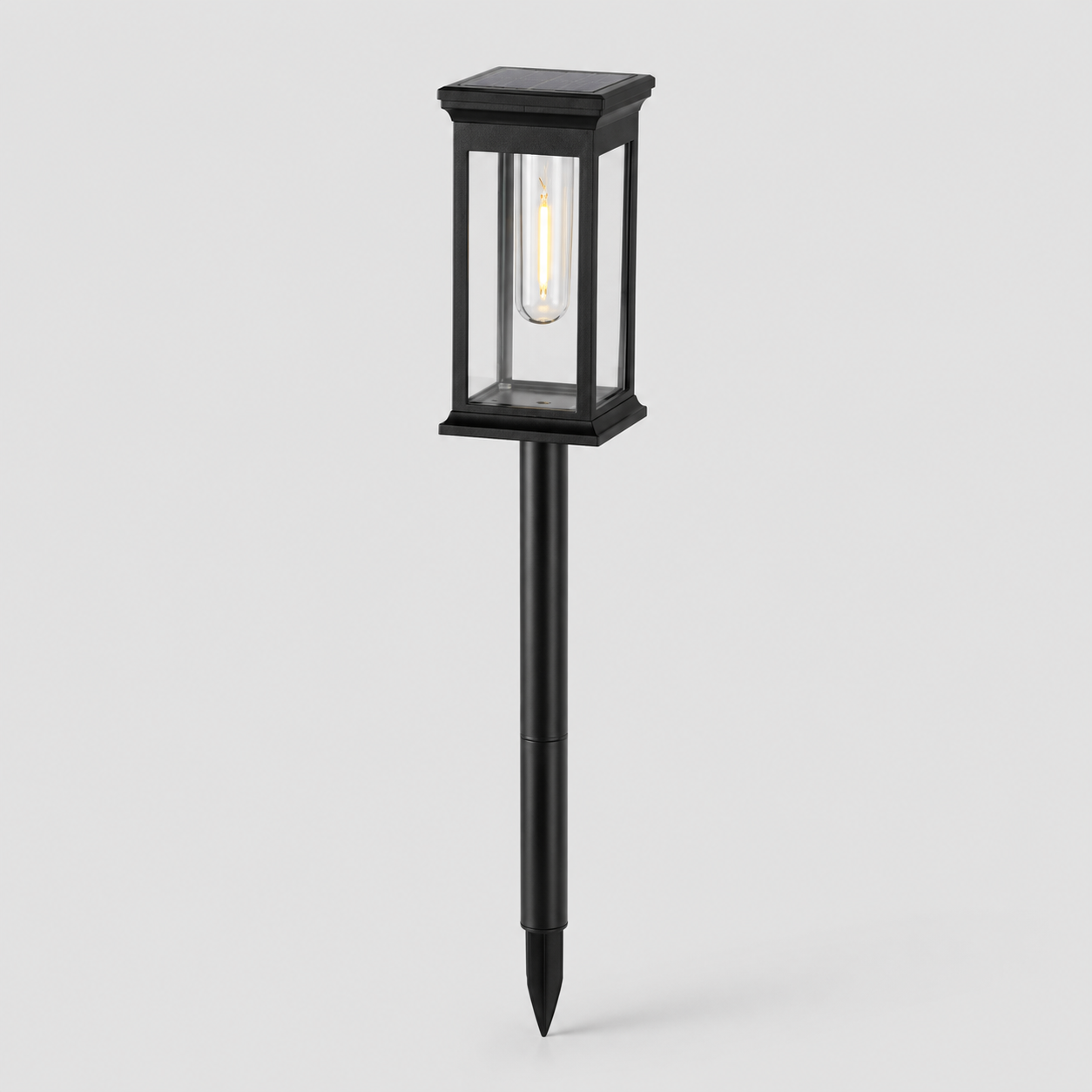 A black solar-powered outdoor landscape light with a rectangular glass lantern-style shade and a stake base, shown against a light gray background.