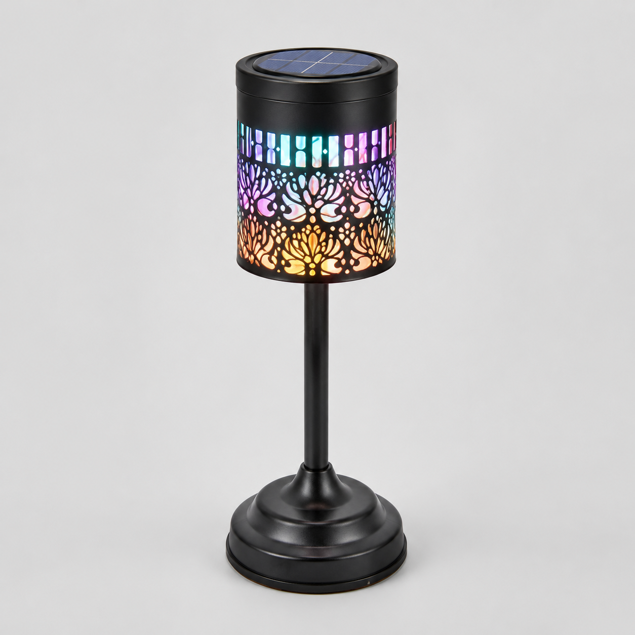 A black cylindrical solar-powered outdoor light with a colorful LED light-up pattern, featuring a floral cutout design that glows with pink, blue, purple, and orange hues, shown on a neutral gray background.