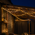 Solar rope lights weave beneath a covered porch roof at deep blue hour.
