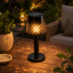 Cordless solar lantern lamp with patterned metal shade casting a warm shadow pattern at dusk