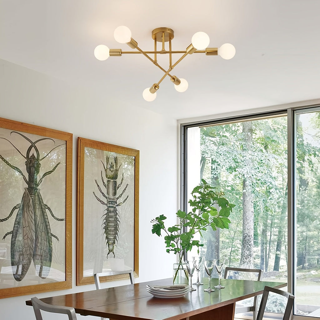 Gold Sputnik ceiling light above a dining table beside tall windows.