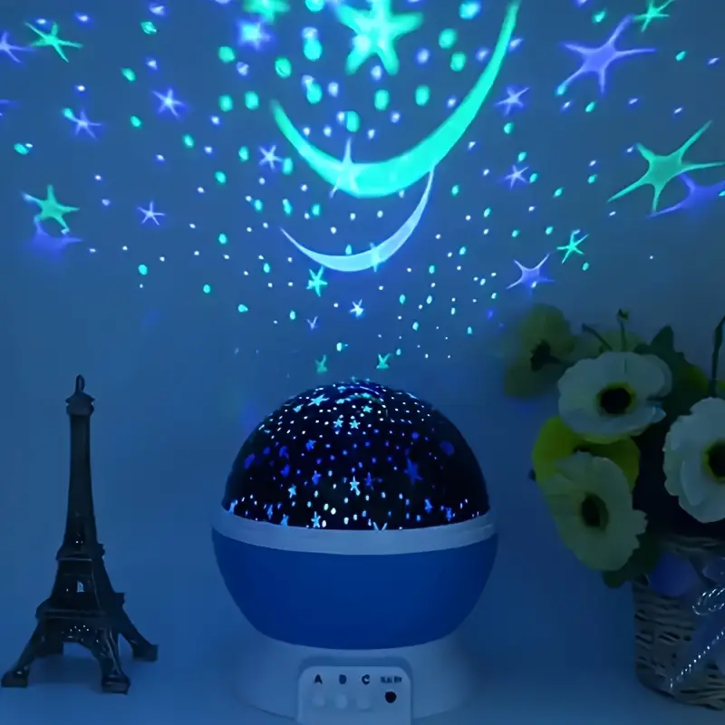 Blue star projector casting moon and star shapes onto a wall.