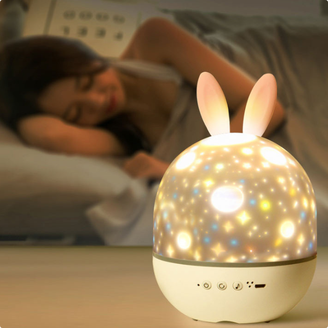Star projector night light shown beside a bed with rabbit ear details