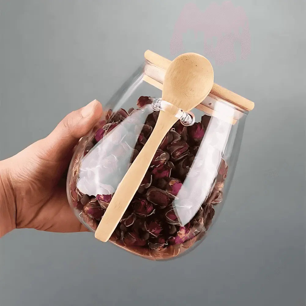 Glass storage jar with bamboo lid and spoon held at its side
