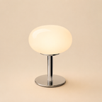 White oval glass table lamp isolated on a warm beige background.