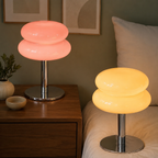 Pink and yellow sculptural glass table lamps glowing in a modern bedroom.